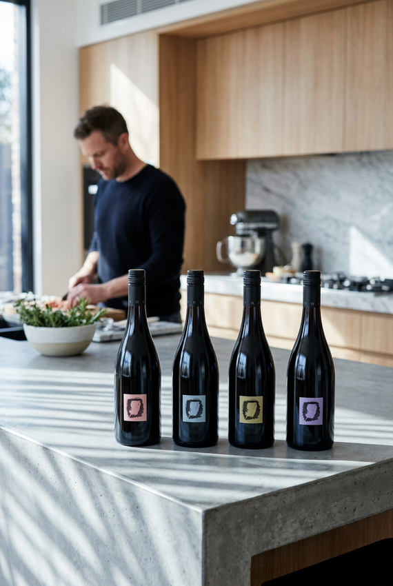 Four dark wine bottles with minimalist square labels in pink, gray, gold, and purple, arranged side by side on a white background.