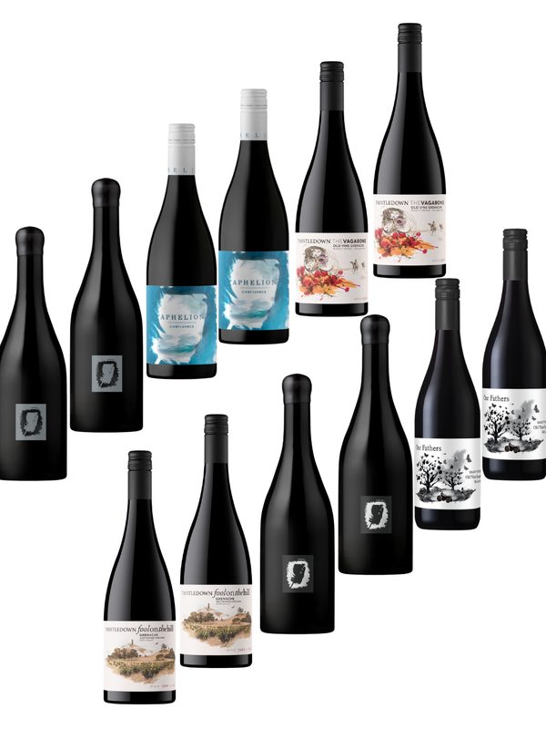 A group of wine bottles arranged on a plain white background, including several dark bottles with labels and a few lighter bottles with blue, white, and scenic illustrations on the labels.